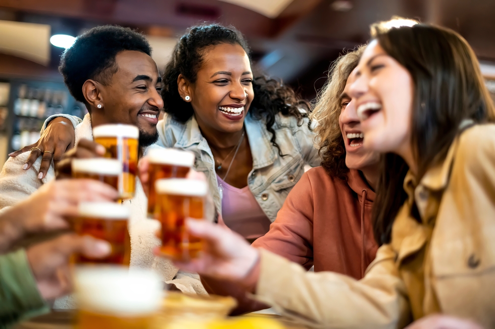 Group,Of,Smiling,Friends,Drinking,And,Toasting,Beer,At,Bar